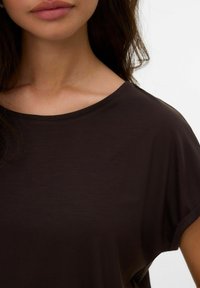 Haut marron à manches courtes en tissu doux et léger ; il présente un col large et une conception de épaules sans coutures pour une coupe décontractée.
