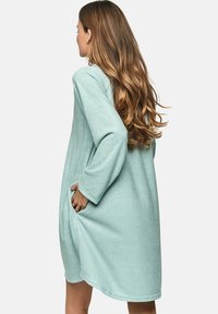 Muntgroene fleece huisjas met lange mouwen, zijzakken en een ontspannen pasvorm, met een zachte textuur en een knielange snit.