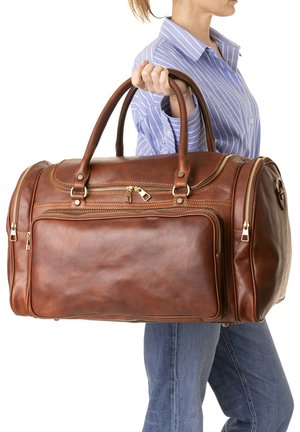 Braune Leder-Duffel-Bag mit goldfarbenen Reißverschlüssen, zwei Griffen und Fronttasche; glatte Textur und abgerundete Form.