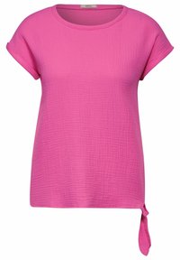 Blusa corta fucsia a manica corta con scollatura rotonda, tessuto testurizzato e un dettaglio annodato sul lato destro inferiore.