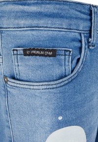 Light blue denim jeans with a prominent back pocket, featuring a black label "2Y PREMIUM ONM" and a white abstract shape design.
