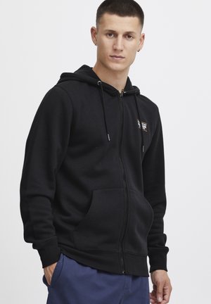 Black zip-up hoodie made of soft cotton blend fabric. Features two front pockets, adjustable drawstrings, and a small logo on the chest.