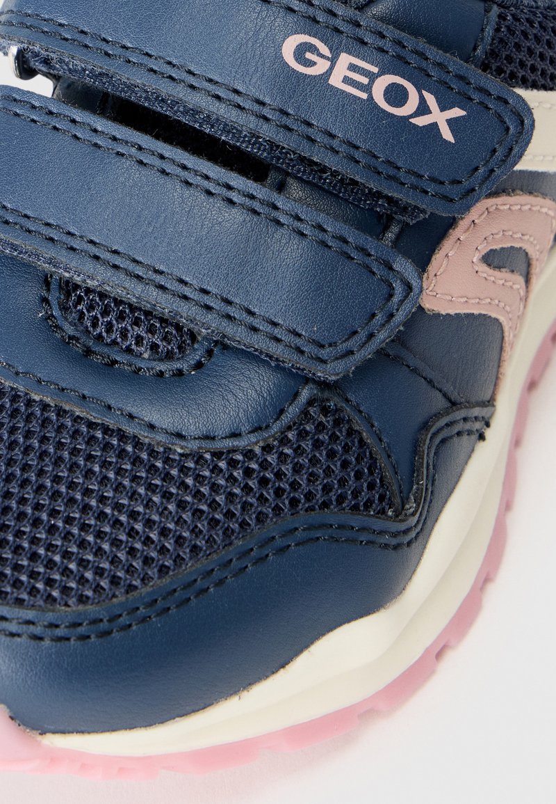 Baskets en cuir et mailles bleues avec des bandes Velcro, présentant une accentuation rose et une semelle en caoutchouc texturé rose. Marque Geox visible.