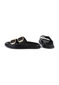 Black slide sandals featuring two large gold buckles, made from a smooth leather material with a flat sole and open back design.