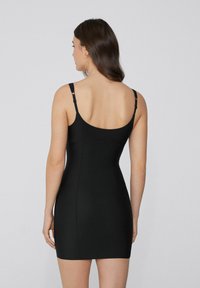 Czarna dopasowana sukienka z regulowanymi ramiączkami, gładką teksturą i prostym designem. Posiada okrągłe plecy i minimalne detale.