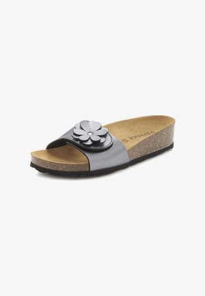 Black slide sandal featuring a floral leather accent, cork footbed, and supportive sole. Smooth upper and natural texture on footbed.