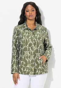 Chaqueta verde con un patrón de formas abstractas en blanco, diseño con cuello, cierre de botones, mangas largas y bolsillos frontales. La tela parece tener textura.