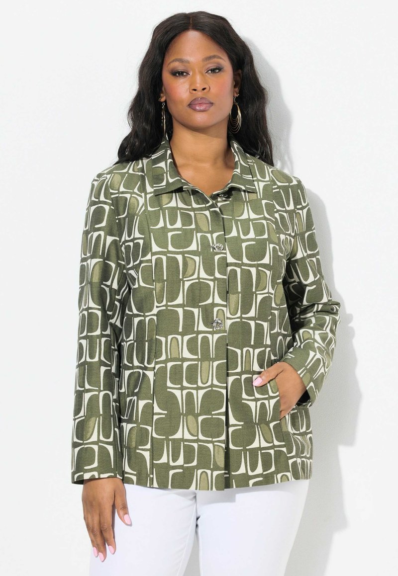 Chaqueta verde con un patrón de formas abstractas en blanco, diseño con cuello, cierre de botones, mangas largas y bolsillos frontales. La tela parece tener textura.