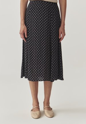Navy midi skirt with a floral print in cream and pink. Soft fabric, A-line shape, and hemline falling just below the knee. Paired with beige shoes.