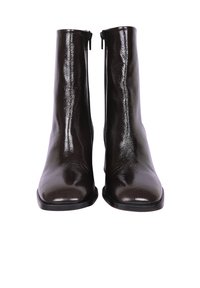 Bottines en cuir verni marron avec une texture lisse, une coupe droite et des zips sur le côté. Équipées d'une semelle noire plate et d'un design minimaliste.
