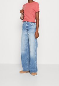 Ljusrosa t-shirt som matchas med vida ljusblå denimjeans. Jeansen har hög midja och klassisk femficksdesign.