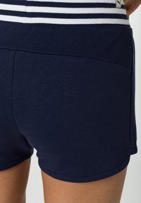 Mörkblå bomullsshorts med midjeband i vita ränder, med en rektangulär bakficka och en slät, mjuk struktur.