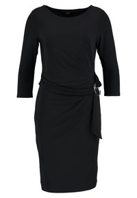 Černé šaty z měkké tkaniny, s kulatým výstřihem, tříčtvrtečními rukávy, překládaným předním dílem a bočním uzlem se kruhovým kovovým detailem.