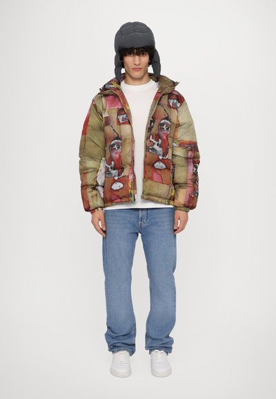 Puffer jacket with a colorful abstract pattern, featuring a zip closure, hood, and a beige base color. Paired with light blue jeans and white sneakers.