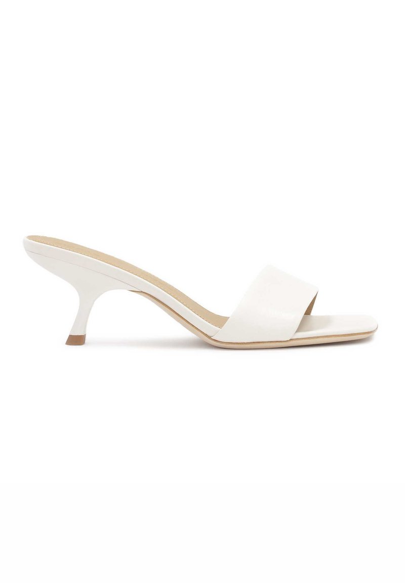 Witte open-toe muiltjes met een brede, gladde band en een slanke, gebogen hak. Materiaal lijkt glanzend met een beige binnenzool.
