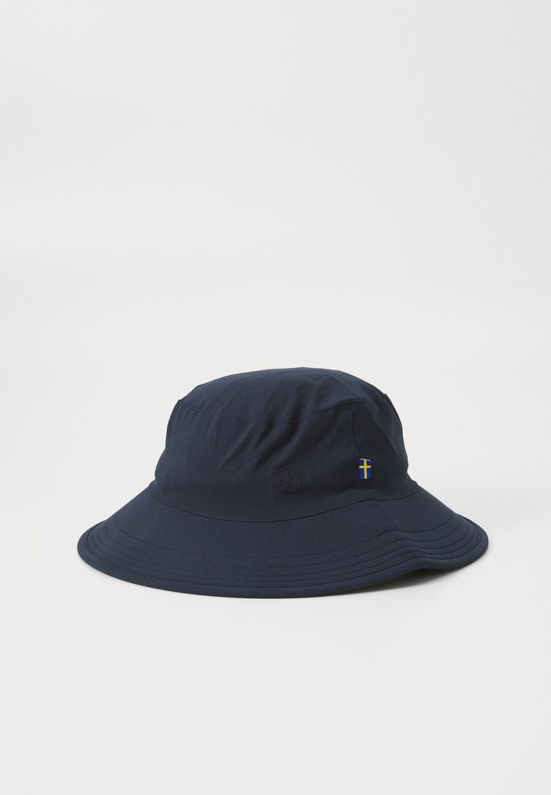 Chapéu de balde azul-marinho com uma superfície texturizada, copa redonda, aba para baixo e um pequeno detalhe da bandeira sueca de um lado.