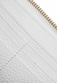 Clutch in pelle bianca con un design trapuntato testurizzato e strisce verticali. Chiusura con cerniera dorata lungo il bordo superiore.