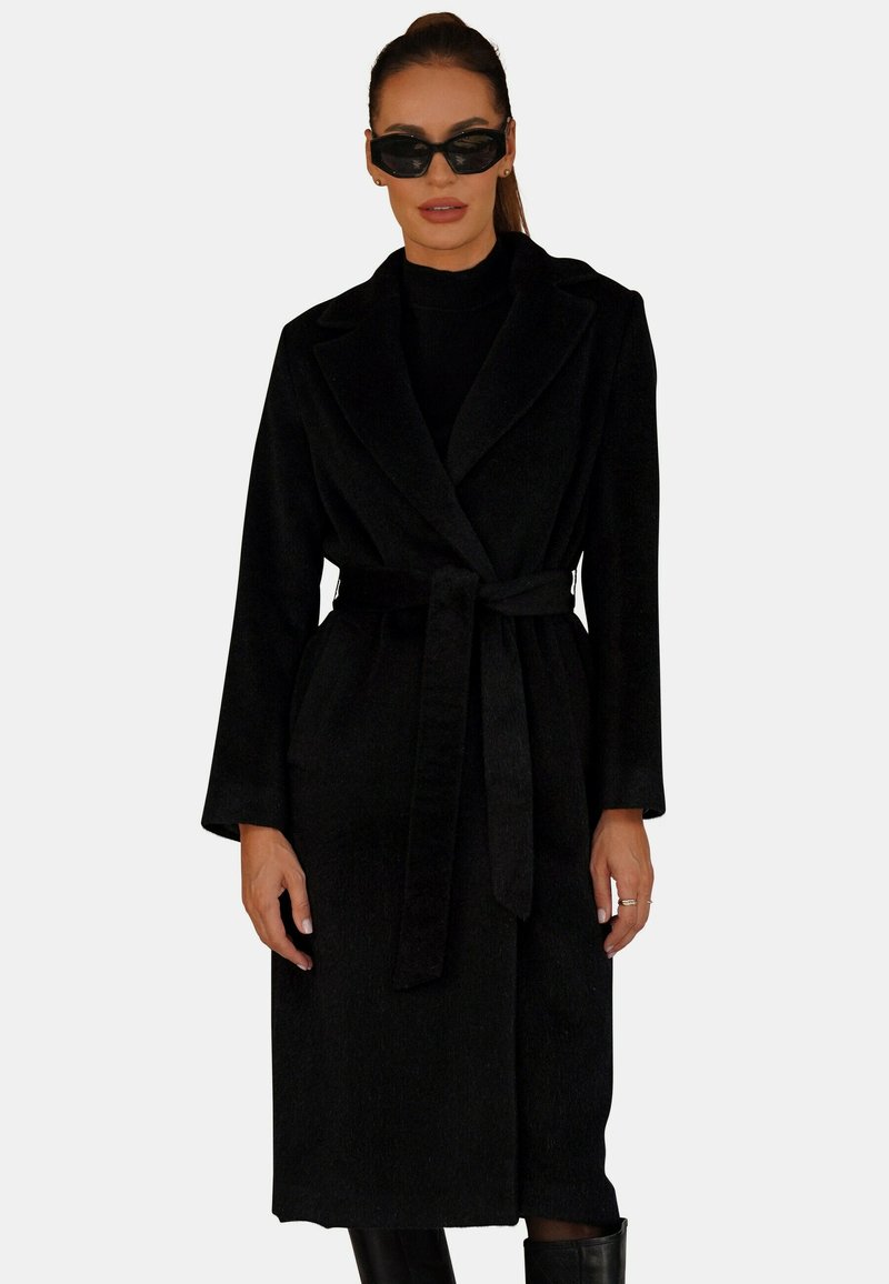 Czarny długi płaszcz z wiązaniem w talii, szerokimi klapami i długimi rękawami, wykonany z teksturowanej tkaniny o gładkim wykończeniu. Minimalistyczny design, bez wzorów.