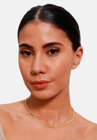 Gold-colored metal necklace with a smooth, sleek design, resting on bare skin, showcasing a minimalist, contemporary style.