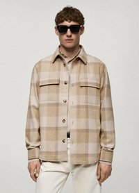 Cămașă din flanel cu model tartan bej, cu două buzunare pe piept, închidere cu nasturi și manșete. Are o textură moale, croială lejeră și tonuri de culoare calde.