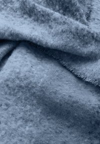 Tejido azul texturizado con un acabado suave y peludo, que presenta un patrón sutil y bordes deshilachados, creando una apariencia de capas.