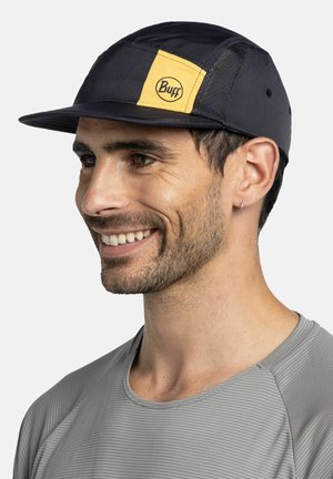 Gorra negra con un parche rectangular amarillo que muestra el logo "Buff", hecha de material ligero; diseño elegante con una visera curva.