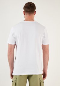 White cotton t-shirt with short sleeves and a crew neck, shown from the back. Smooth texture, plain design without patterns or accents.