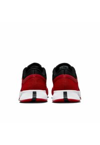 Zapatillas deportivas rojas con una parte superior texturizada, acentos negros y una suela blanca con una franja negra en el talón, vistas desde atrás.