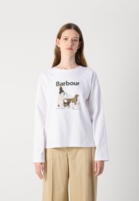 T-shirt blanc à manches longues avec un imprimé graphique représentant une personne marchant trois chiens, avec le texte "Barbour" en vert. Encolure ronde simple.
