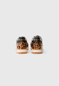 Et par sneaks i brun og sort leopardprint med sorte hælstriber og hvide såler, set fra baggrunden på en hvid baggrund.