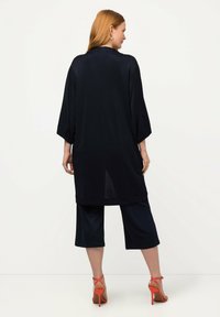 Námořnický kimono stylový župan s širokými rukávy, se bočním rozparkem a hladkým materiálem, kombinovaný s krátkými námořnickými kalhotami a oranžovými sandály na podpatku.