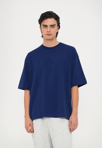 Námornícky modré oversized tričko vyrobené z bavlny, s krátkymi rukávmi a okrúhlym výstrihom, s jemným logom v strede.