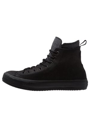 Sort høj-top sneaker med tekstureret tunge, sorte snørebånd, gummisål og trækstrop ved hælen, vist fra ydersiden.