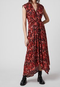 Abito maxi a stampa leopardo rosso e nero con scollatura a V, maniche corte e cintura in vita, realizzato in tessuto fluido. Accentuato con stivali combat neri.
