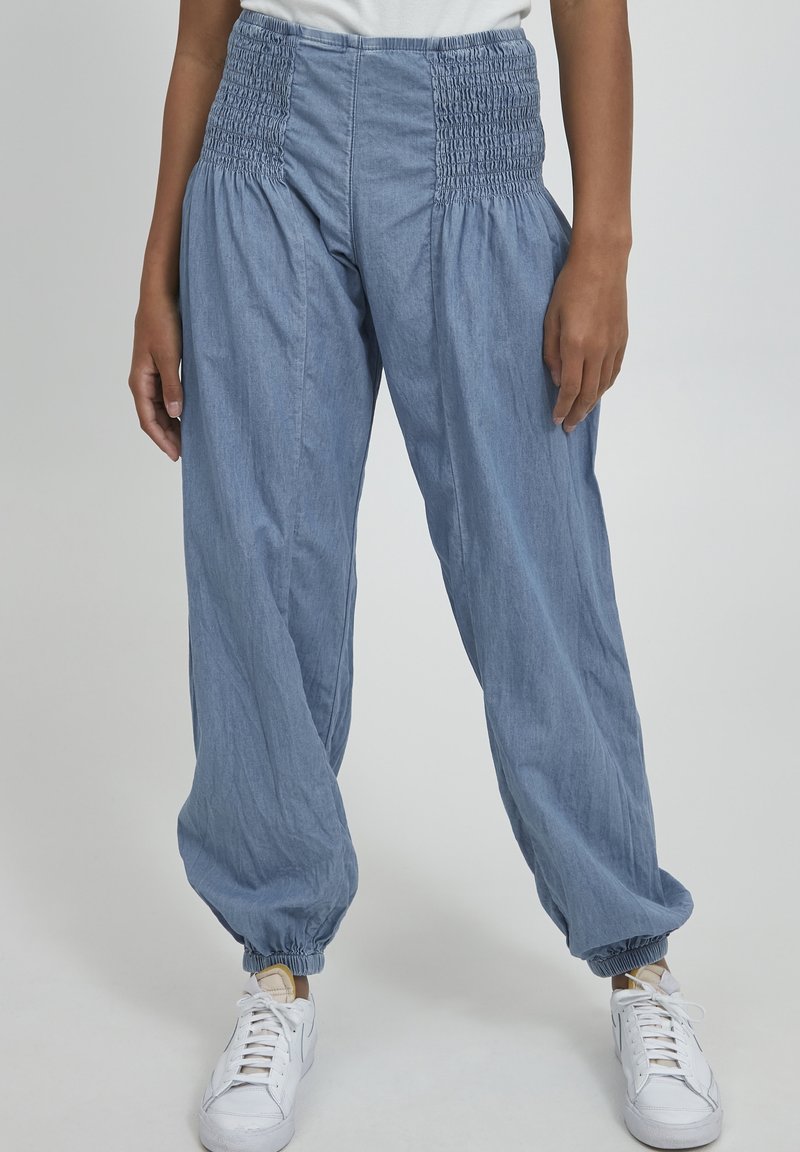 Pantalones sueltos de color azul claro con una cintura alta fruncida y puños elásticos en los tobillos, elaborados con una tela texturizada.