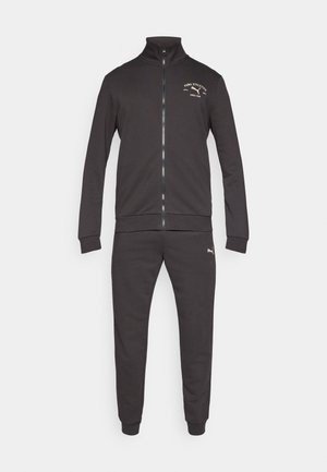 Szary sportowy dres, obejmujący kurtkę zapinaną na zamek z wysokim kołnierzem i ściągaczami na rękawach oraz dopasowane, zwężane spodnie z dopasowanymi nogawkami.