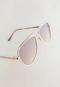 Ochelari de soare din metal auriu, cu un cadru mare și rotunjit și lentile gradient. Prezintă brate subțiri și piese pentru urechi texturate pentru confort.