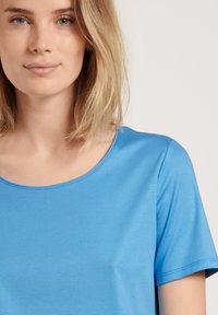 Blauwe T-shirt met korte mouwen van gladde stof met een ronde halslijn en subtiele stiksels, die nauwsluitend op het lichaam valt.