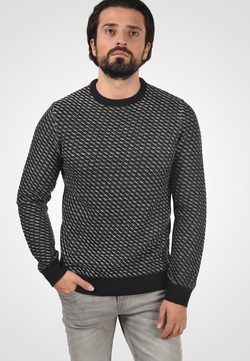 Suéter de patrón blanco y negro con cuello redondo, puños y dobladillo acanalados. Fabricado en tejido de punto, presenta un diseño texturizado.