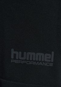Zwarte stof met de merknaam "hummel PERFORMANCE" gedrukt in donkergrijs, gecentreerd en licht gestructureerd.