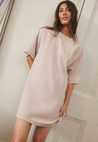 Pastelroze oversized jurk van gestructureerde stof, met korte mouwen, een ronde halslijn en een licht gebogen zoom.