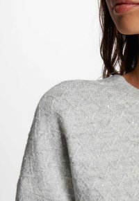 Maglione grigio a maglia con un motivo a rombi testurizzato, con leggeri accenti luccicanti e un design a scollo a barca ampio.