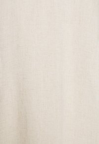 Tissu en lin de couleur crème claire avec une texture subtile, présentant un motif de tissage naturel et un aspect doux légèrement transparent.