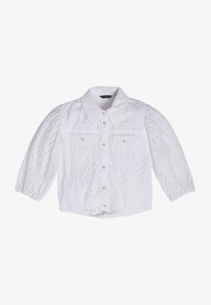 Camicia bianca all'uncinetto con bottoni, maniche a tre quarti gonfie e due tasche sul petto, su uno sfondo semplice.