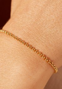 Gold chain bracelet, featuring round links, a smooth texture, and a delicate design, shown resting on a skin-toned wrist.