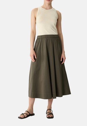 Een licht crèmekleurig geribbeld tanktopje, gecombineerd met een middellange, loszittende olijfgroene rok met een elastische tailleband en platte, zwarte sandalen.