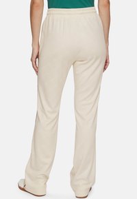 Crème-kleurige sweatpants met een getextureerd hexagonaal patroon, elastische tailleband en een relaxte pasvorm, met zijslits aan de onderkant.