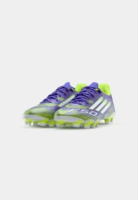 Paarse en limoen groene voetbalschoenen met een gestructureerd oppervlak, voorzien van witte strepen en een lichtgewicht ontwerp met noppenzolen.