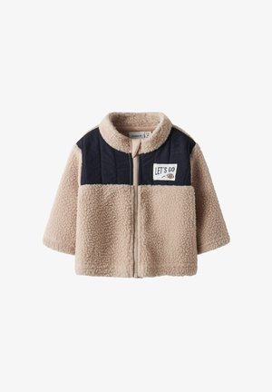 Fleecejakke i beige med marineblå detaljer og glidelås. Har rund krage og et "LET'S GO"-merke foran.