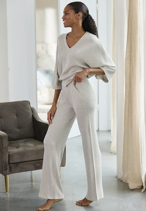 Lichtbeige gebreide loungewear set met een losse V-hals top met brede mouwen en high-waisted, flared broek met zijzakken.